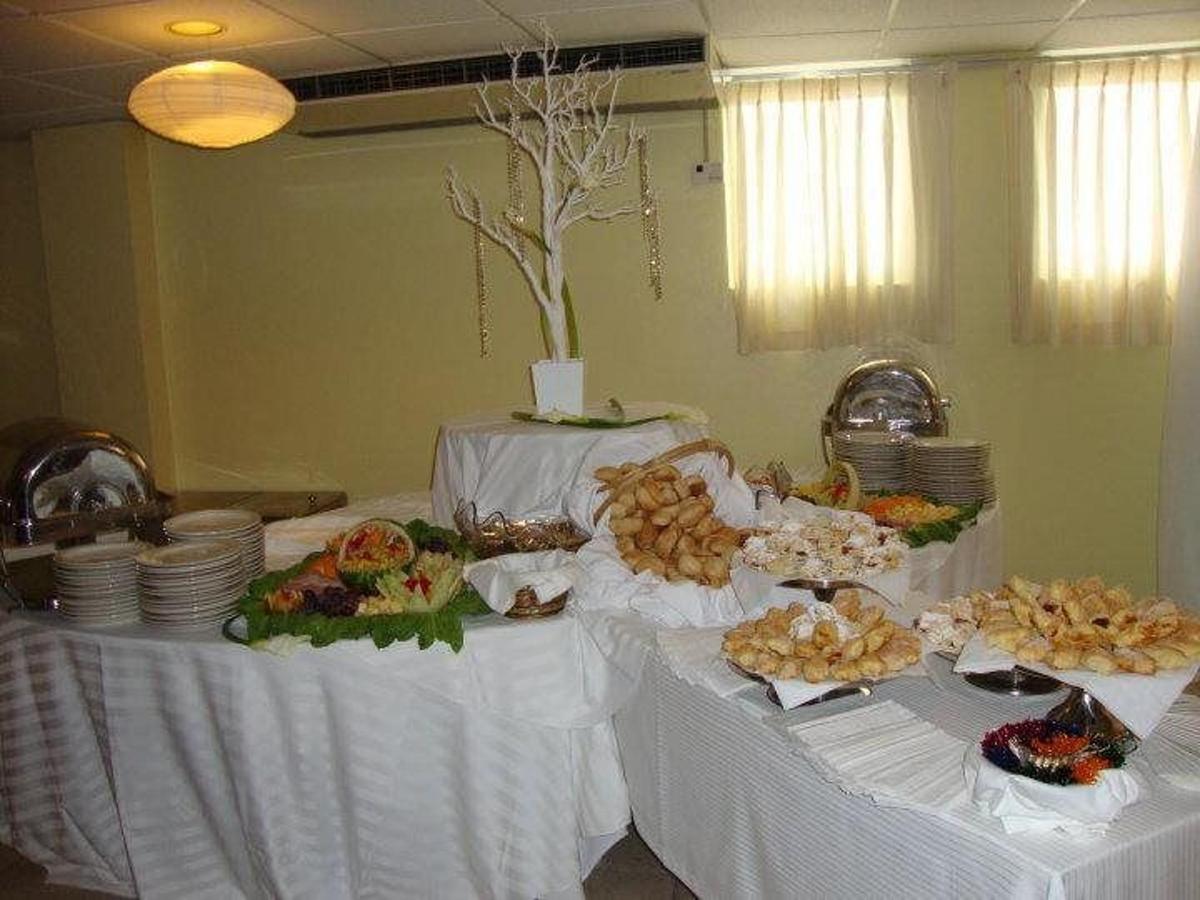 Buffet table setup with pastries and breads on plates, decorated with a white tree centerpiece in an indoor setting