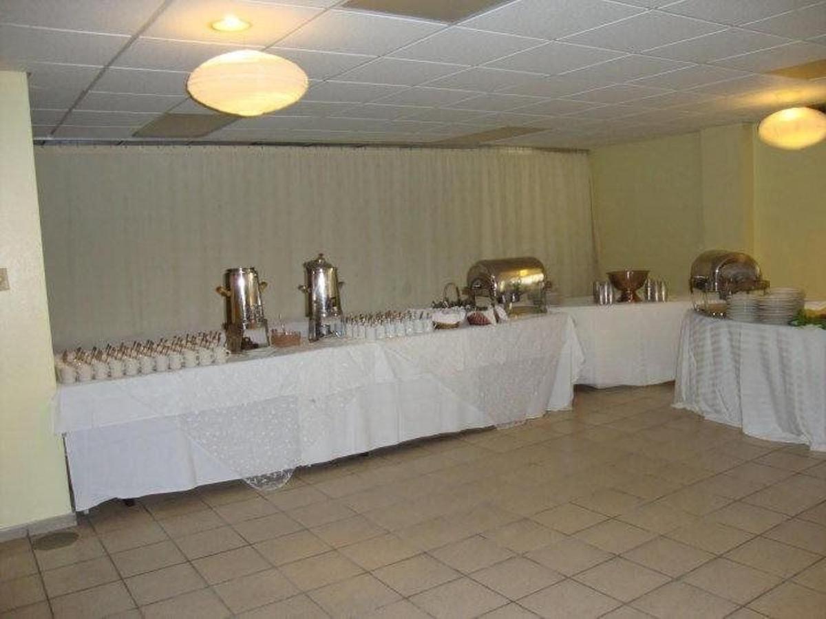 Banquet room set up with buffet tables, chafing dishes, and beverage urns, cream-colored walls and tile floor